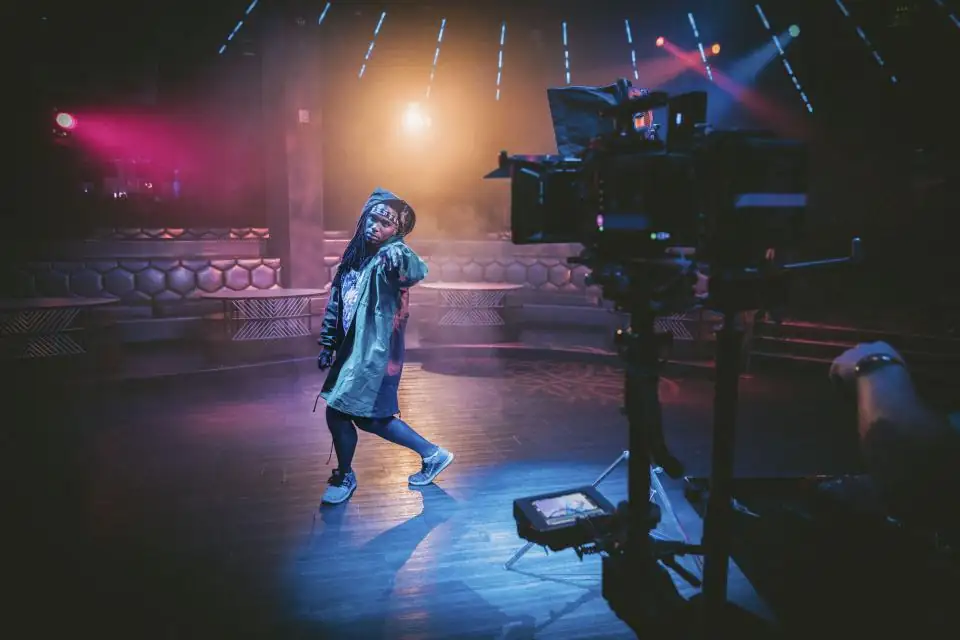 Camera operator filming a performer on a lit stage during a production