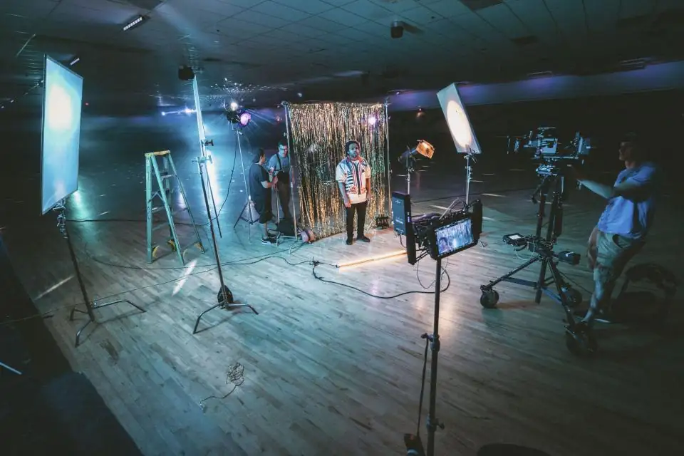 Behind the scenes on a video shoot with lights, monitors and a camera crew on set