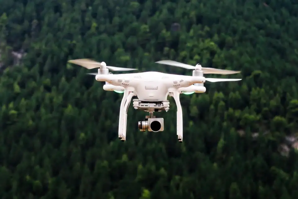 Camera drone in flight over trees