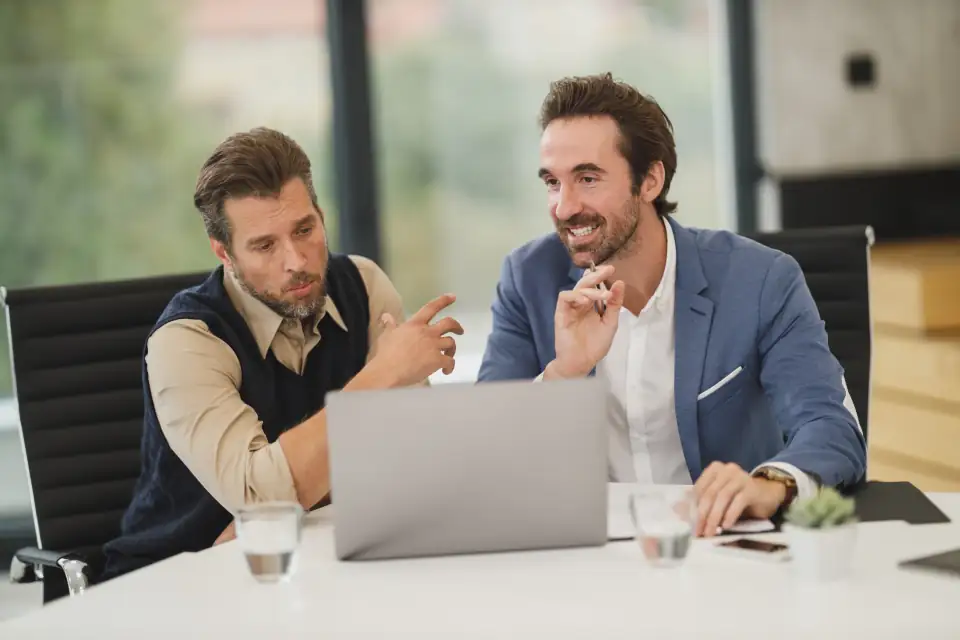 Two colleagues reviewing work on a laptop