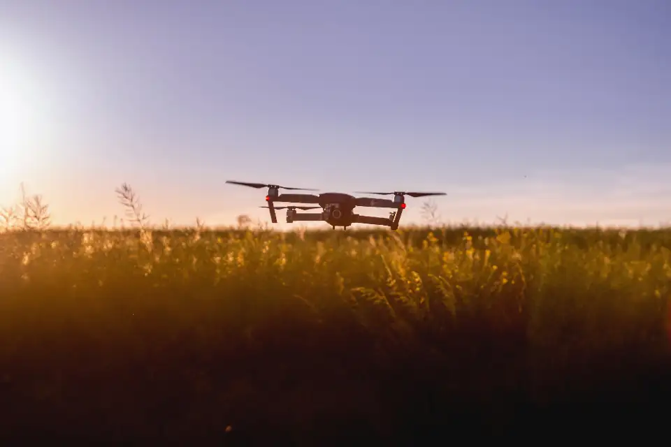 Drone flying over a field at sunset