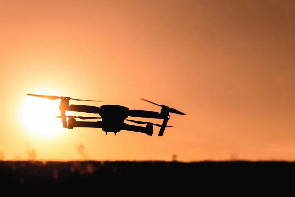 Drone silhouetted against an orange sunset